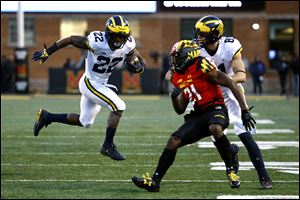 Michigan running back Karan Higdon, left, rushes past Maryland defensive back RaVon Davis (21) and Michigan wide receiver Nate Schoenle. Higdon will be one of the big question marks leading into Saturday's game against Wisconsin.