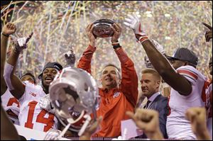Ohio State coach Urban Meyer holds the trophy after Ohio State defeated Wisconsin 27-21 in the Big Ten championship game.