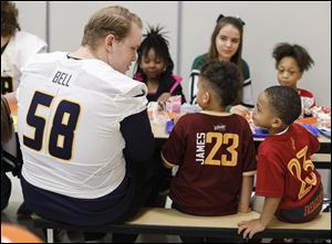 University of Toledo football player Cameron Bell, a tackle from Cleveland, eats lunch with kindergartners Micheal Wealleans and Brad McGlown, right, at Longfellow Elementary School.