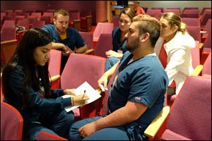 Registered nurses discuss a hospital-based scenario with a victim of domestic violence. They are, clockwise from left: Amber Geitgey, of Toledo [with pen and paper]; Drew Toth, of Maumee; Tacee Graff, of Oregon [partially obscured],  Kayla Carr, of Ida, Michigan, and Jacob Hinojosa, of Temperance, Michigan.  