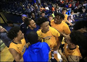 Whitmer players celebrate with their teammate Edward Colbert, center, after his game-winning shot in Saturday's district championship game against Southview.