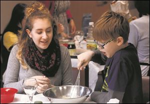 Zoe Kuehn, 15, left, laughs with Cooper Kruse, 10, as they make Hamantashen cookies together in advance of Purim Tuesday, February 13, 2018.
