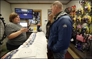 Tiffany Densmore, left, helps Nikki Cassidy, center, and Jim Cassidy, right, of Toledo, get their guns and ammunition during Cleland's Outdoor World's Bullets and Brunch event on April 15, 2018.