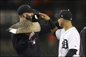 Detroit Tigers shortstop Jose Iglesias touches the team's Canada goose decoy mascot held by pitcher Mike Fiers after the Tigers rallied to beat the Minnesota Twins, 5-2.