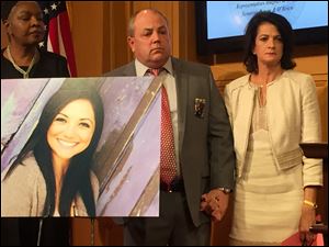 Toby Tokes, center, and his wife, Lisa McCrary-Tokes, stand next to a photo of their murdered daughter, Reagan.