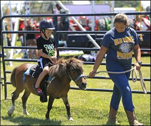 Konner Stole of Oak Harbor rides a pony that is being guided by Joanna Barns of Fremont during the Ottawa County Fair in 2017.